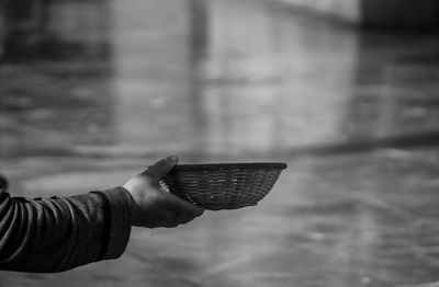 Cropped image of beggar holding wicker bowl