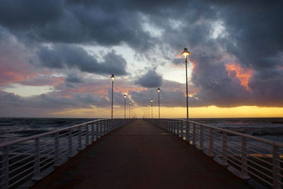 Pier over sea against sky during sunset