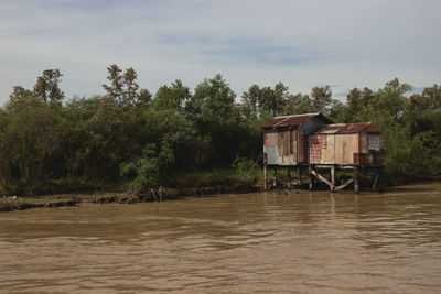 House by river against sky