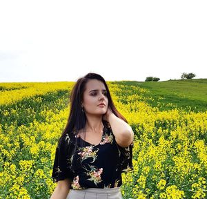 Portrait of beautiful young woman standing on field