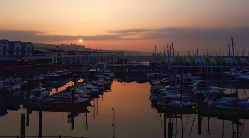 Sailboats moored at harbor during sunset