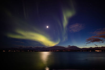 Reflection of aurora polaris on lake against sky