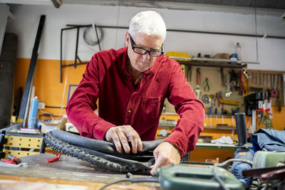 Senior man repairing bicycle tire in garage