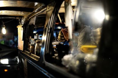 Man making coffee in motor home seen through window at night