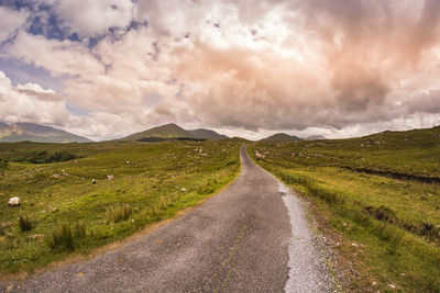 Road amidst field against sky