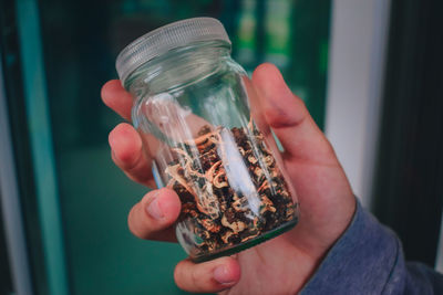 Midsection of person holding glass jar