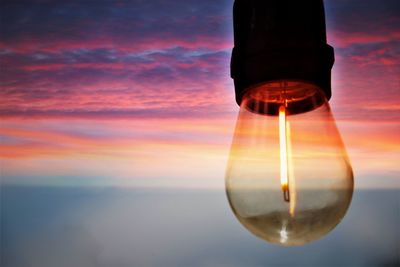 Close-up of illuminated light against sky during sunset