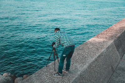 Man holding umbrella standing by sea