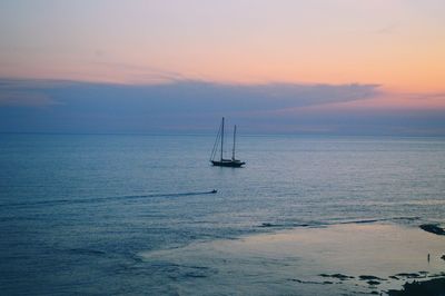 Sailboat sailing on sea against sky during sunset