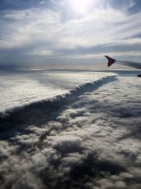 Airplane flying over sea against sky during sunset