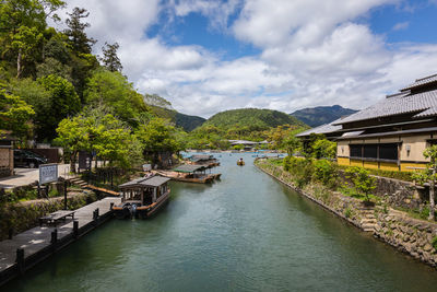 River amidst buildings and trees against sky