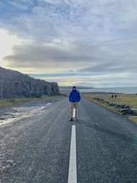 Rear view of man walking on road against sky