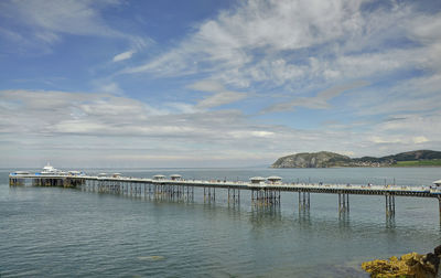 Pier on sea against cloudy sky