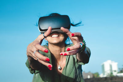 Young woman using mobile phone against blue sky