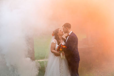 Full length of newlywed couple standing by abandoned built structure