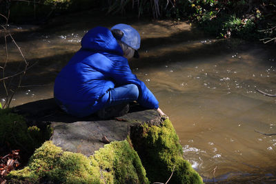 Side view of man sitting on rock