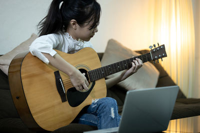 Cute girl playing guitar at home