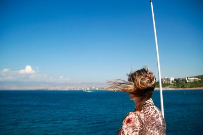 Rear view of woman looking at sea against blue sky