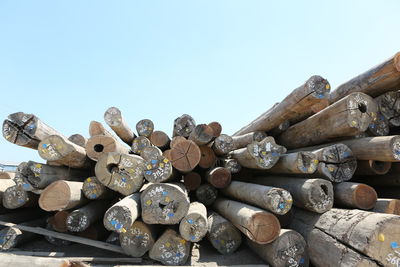 Low angle view of stack of firewood against clear sky