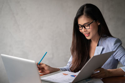 Young woman using mobile phone while sitting on table