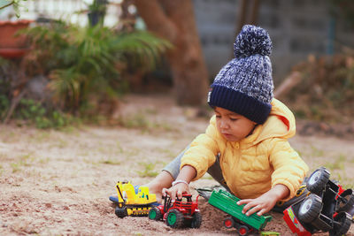 Cute boy playing with toys while sitting on land