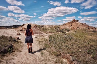 Rear view of woman standing in badlands against sky