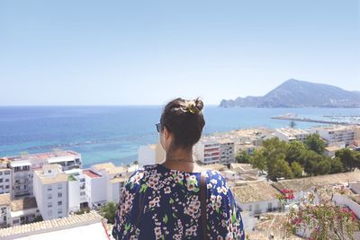 Rear view of woman looking at sea against clear blue sky