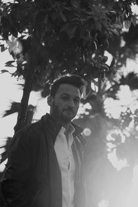 Portrait of young man standing by tree