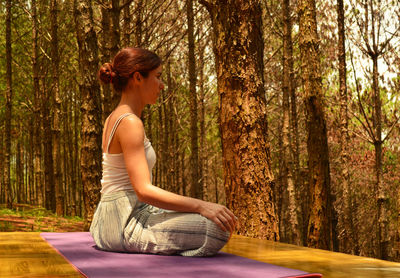 Side view of woman sitting in forest