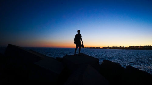 Silhouette man standing on beach against clear sky