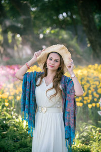 Portrait of smiling young woman standing against plants