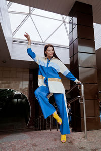 Happy woman sitting on floor against blue wall