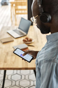 Man listening music through headphones using smart phone at home