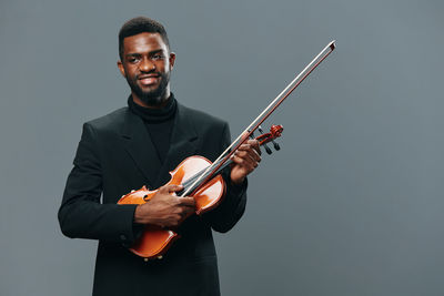 Portrait of man holding violin against white background