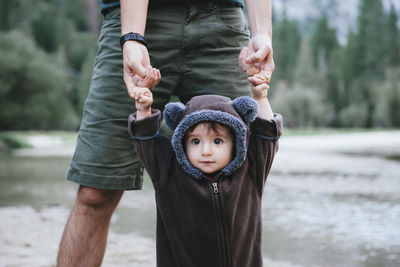 Midsection of father holding daughter's hands while standing by lake at yosemite national park