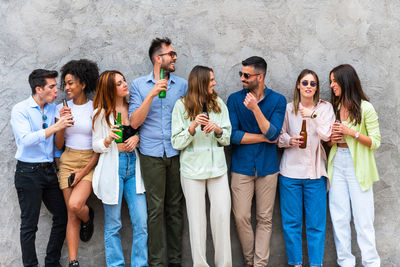 Multiethnic young people toasting and drinking with beer bottle.