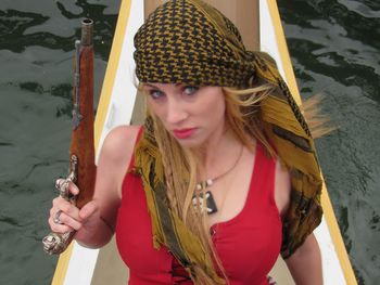 Portrait of female pirate holding gun on boat in sea