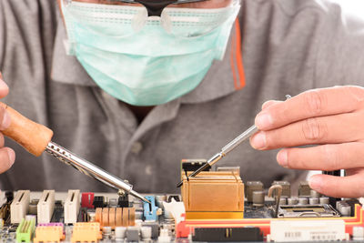 Midsection of engineer repairing mother board 