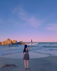 Rear view of man standing at beach against sky