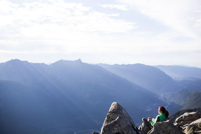 High angle view of woman relaxing on rocks against mountain range