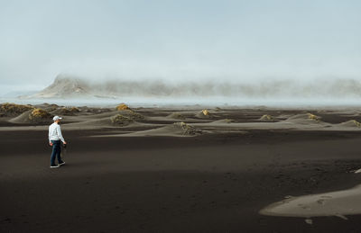 Rear view of man standing on land against sky