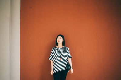 Woman standing against orange wall