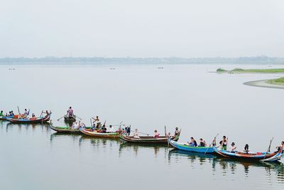 People sitting on riverbank against sky