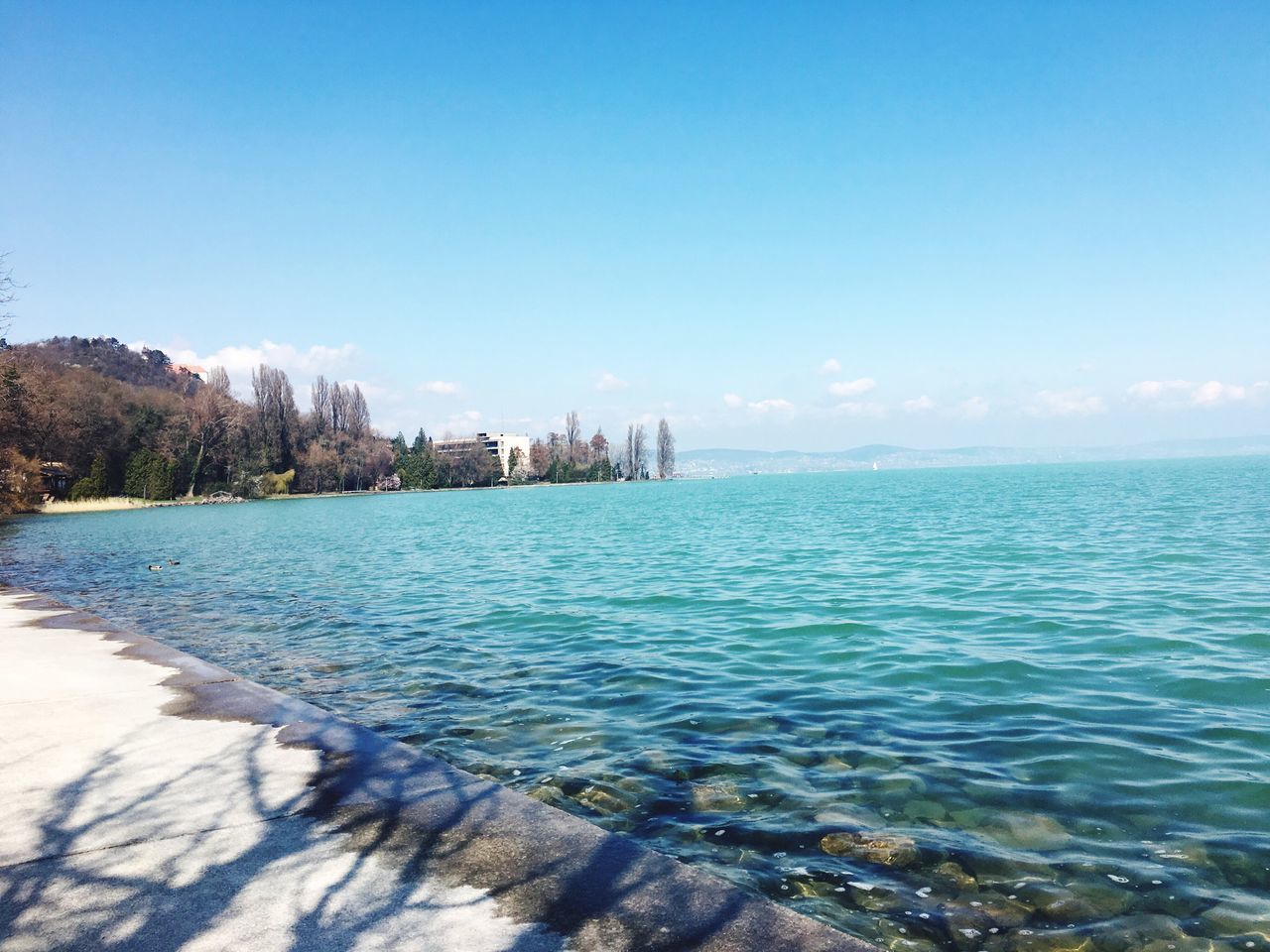 water, sea, blue, clear sky, copy space, building exterior, built structure, architecture, tranquil scene, scenics, tranquility, beauty in nature, sky, horizon over water, nature, waterfront, tree, rippled, day, outdoors