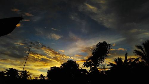 Low angle view of silhouette trees against cloudy sky