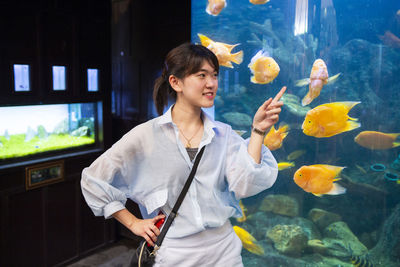 Young woman standing in fish tank at aquarium