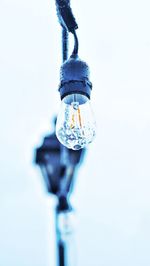 Low angle view of light bulbs hanging against clear sky