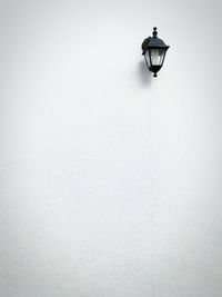 Low angle view of illuminated street light against wall