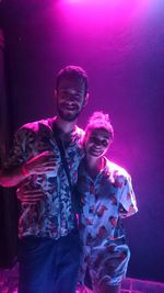 Young man smiling while standing against pink light