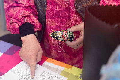 Midsection of woman holding souvenir while pointing at paper on table